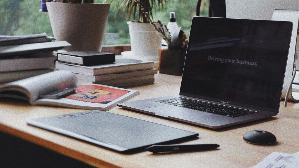 A computer sits on a desk with a drawing tablet and designer magazine