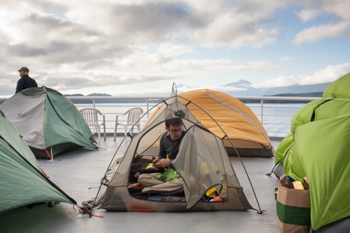 Mike Viotti sits in his tent on the top deck of the Columbia, one of the ships in the Alaska Marine Highway ferry system, which takes passenger through the Inside Passage of Alaska, on Saturday, July 13, 2013. (Photo by Matthew Ryan Williams for The New York Times)