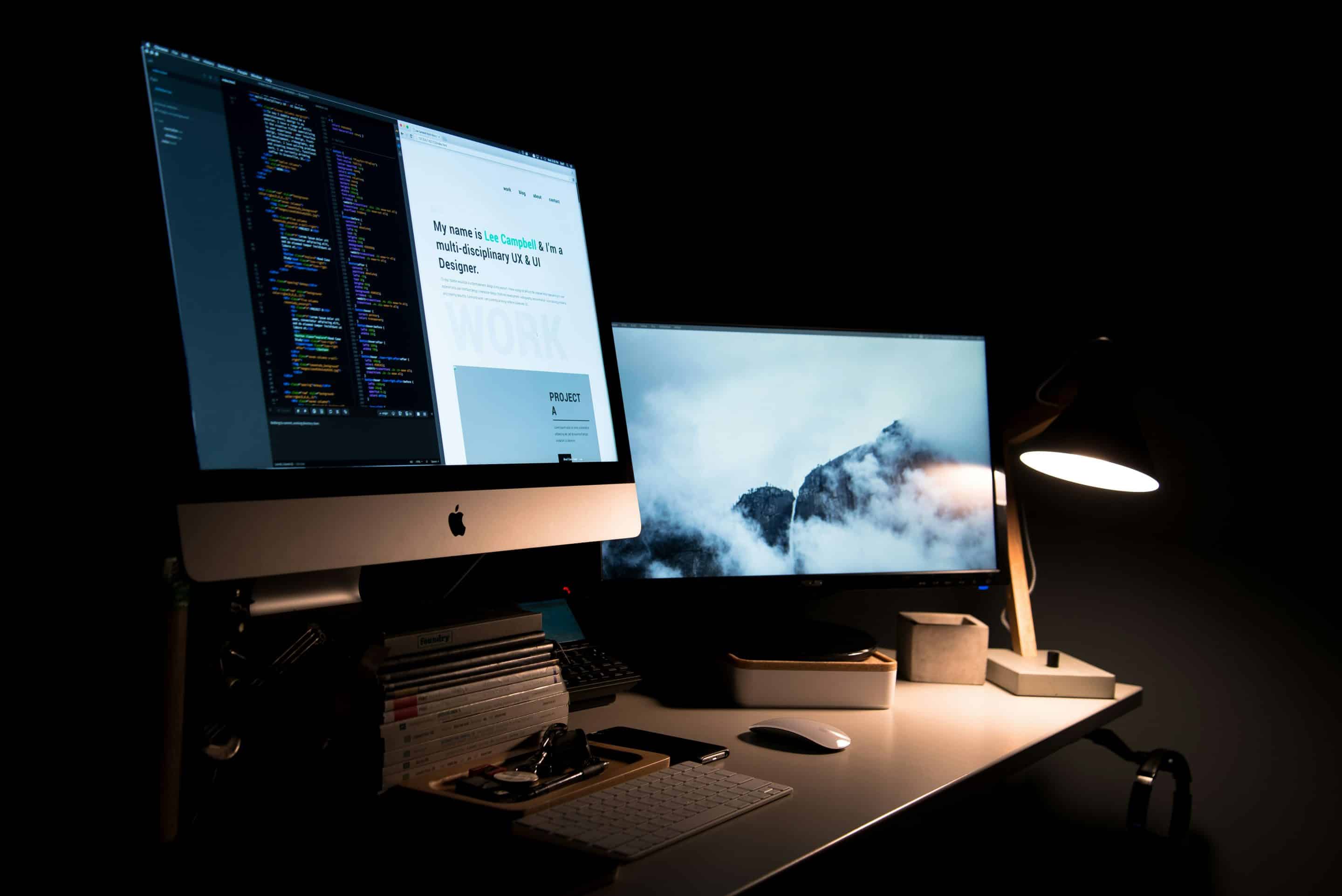 two monitors, one displaying code and an interface