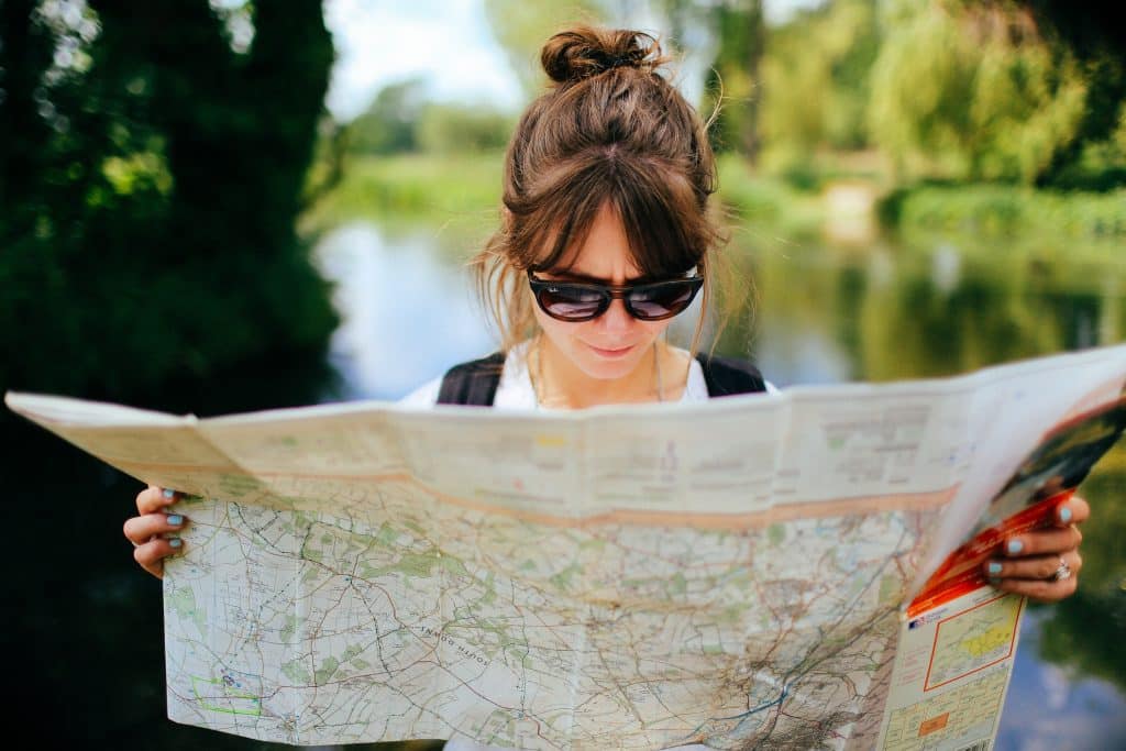 Woman reading a map in front of a lake