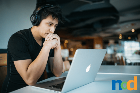 Student wearing headphones thinking at a laptop